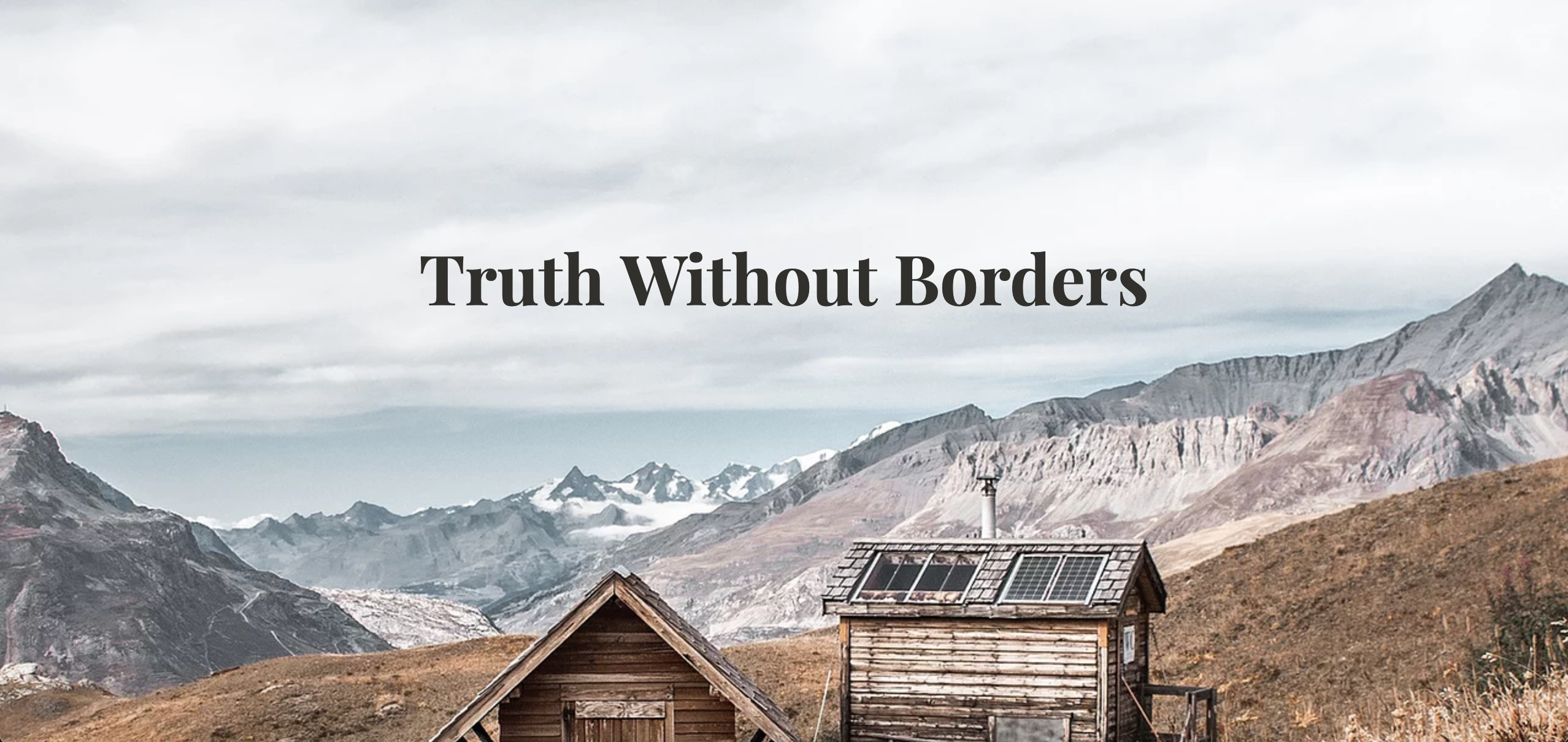 Cabins against mountains with 'Truth without Borders' overhanging it