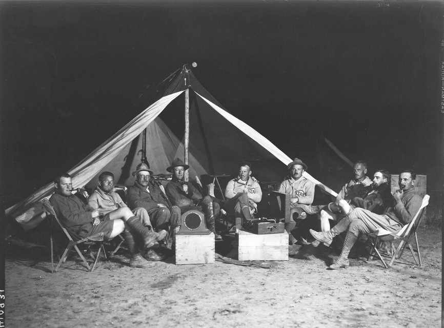 Photograph of expedition members outside a tent listening to music on a victrola.